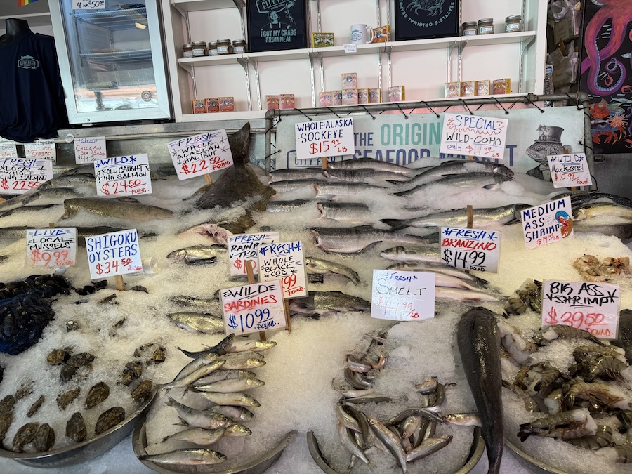 Whole fish and shellfish arranged in neat rows at a seafood market.