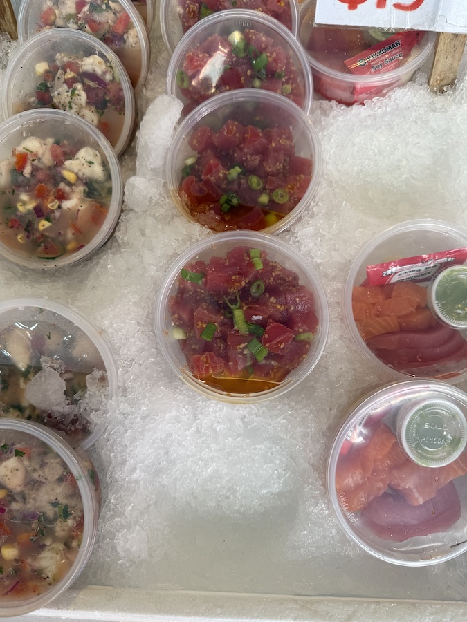 Freshly prepared seafood salads featuring tuna and salmon, kept cool on a bed of ice for maximum freshness.