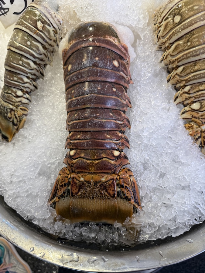 Lobster tails on ice, ready for purchase, with visible texture and natural color variations.
