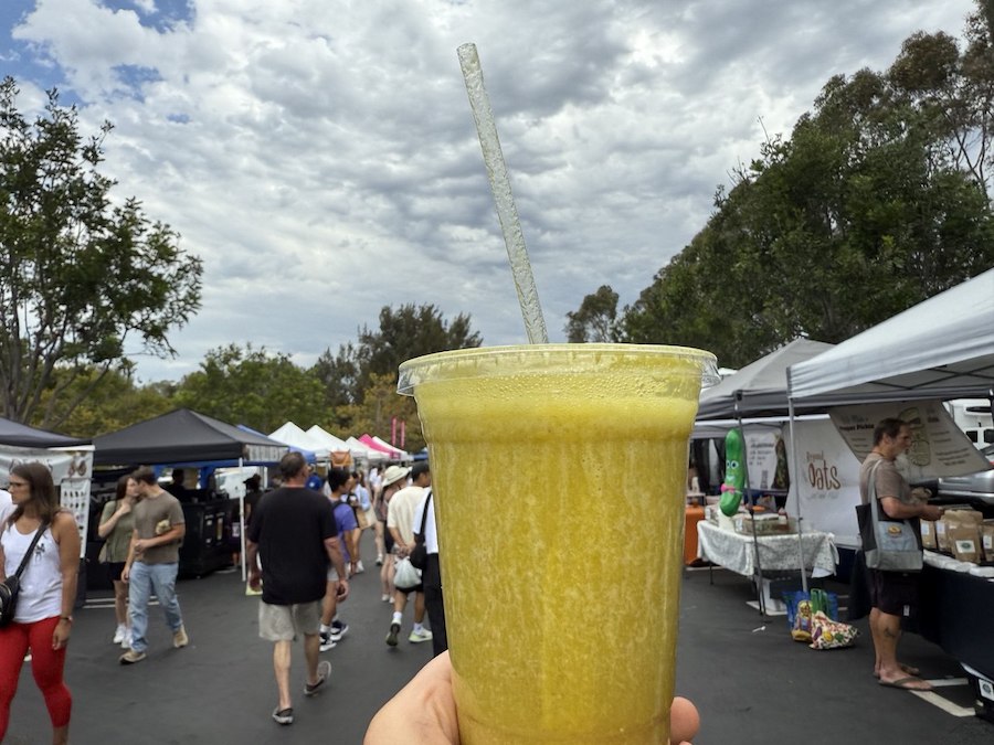 A shopper holding a cup of cold, freshly pressed juice.