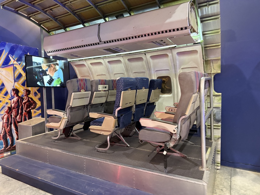 An exhibit of an airplane's fuselage section with several rows of passenger seats.