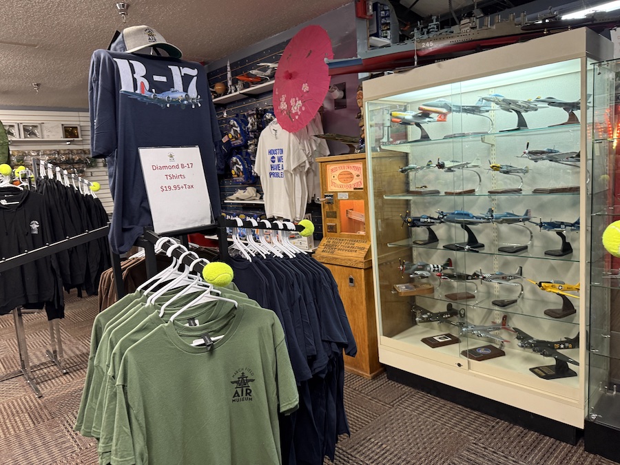 A museum gift shop area filled with various merchandise, including T-shirts, model airplanes, and books.