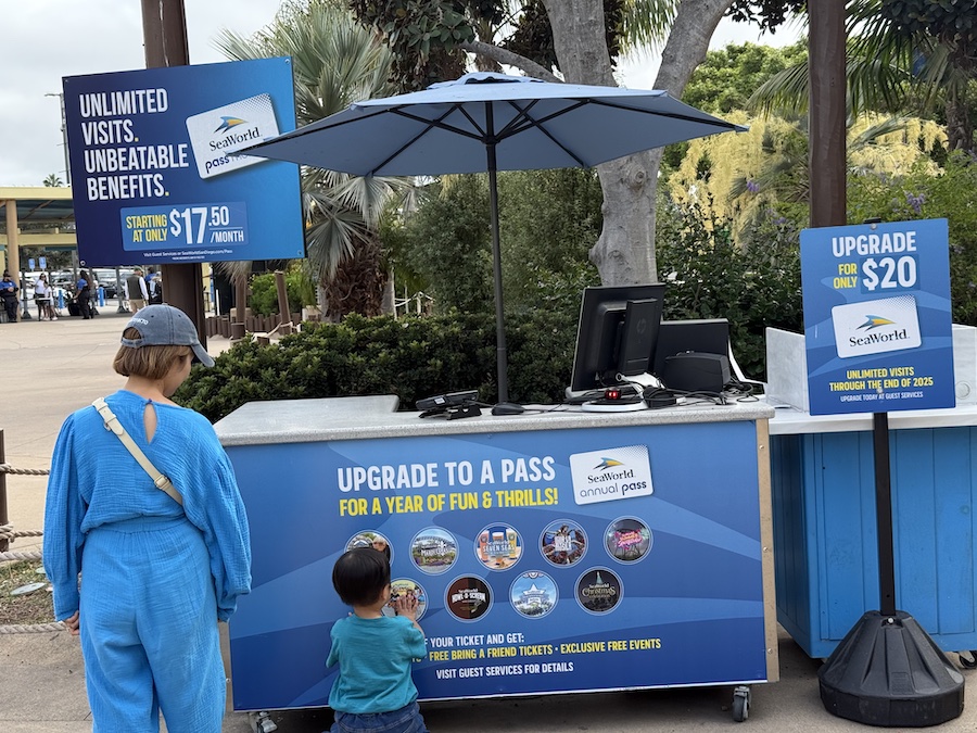 A SeaWorld San Diego guest services kiosk advertising annual passes and upgrades.