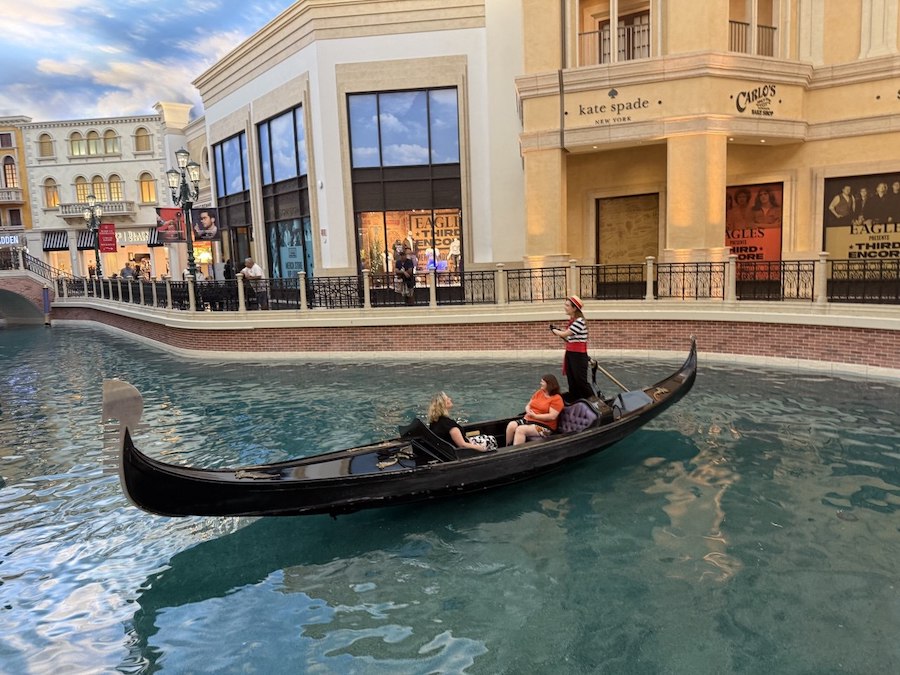 Visitors taking a romantic gondola ride beneath bridges inside The Venetian’s canal system.