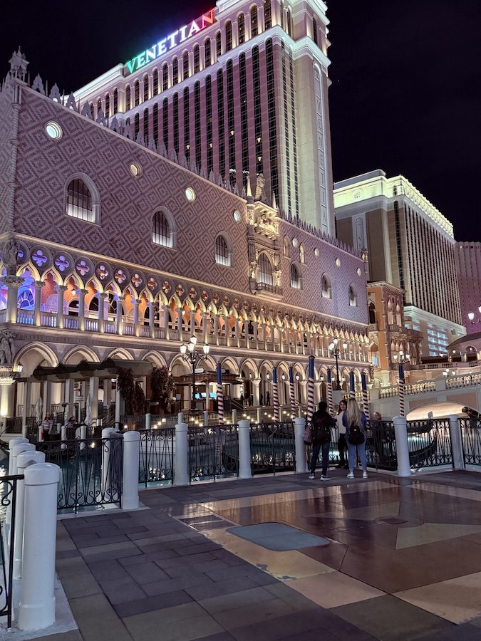 A wide shot of The Venetian’s exterior lit up at night.