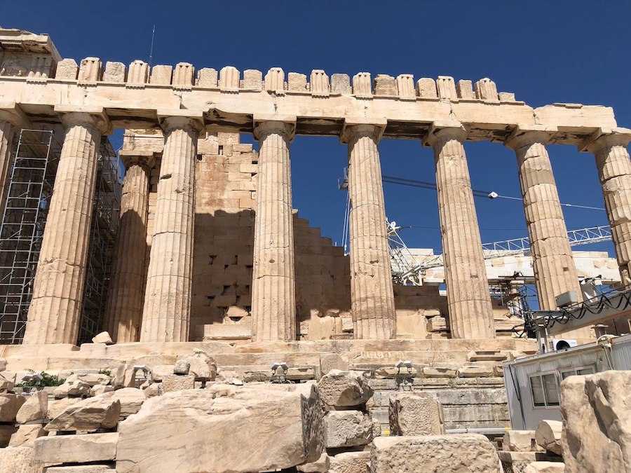 The ancient columns of the Acropolis glow in the golden sunlight.