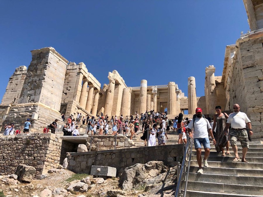 Tourists descend the stone stairs from the entrance to the Acropolis.