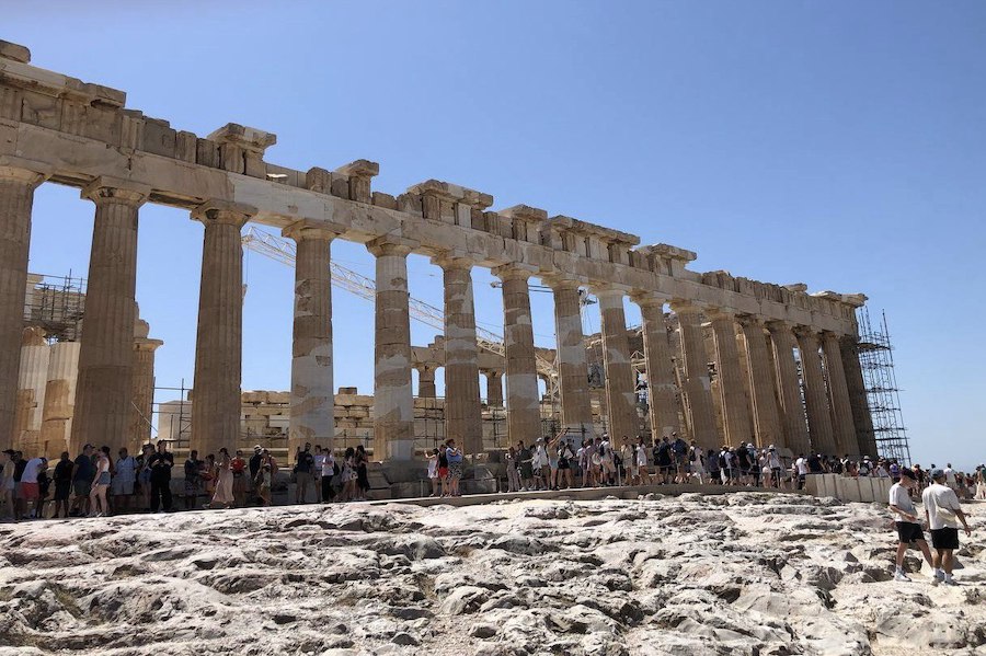 Tourists walking up the stone pathway leading to the Acropolis entrance.