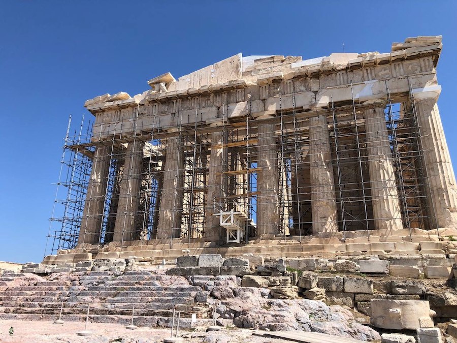 The Parthenon bathed in golden sunlight against a clear blue sky.