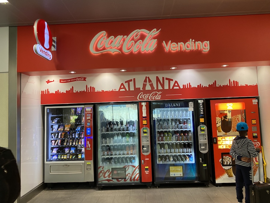 A bright red Coca-Cola vending machine in the concourse at Atlanta Airport.