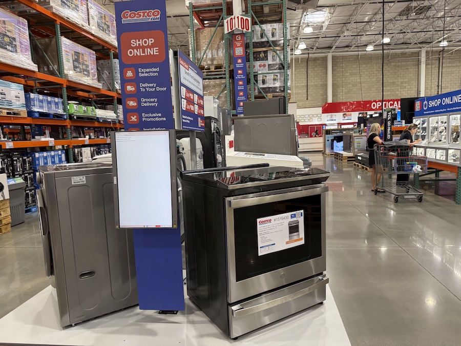 Banner display inside Costco promoting online shopping and delivery services.
