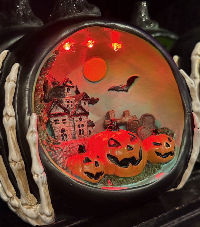 A nightlight with pumpkin and haunted house that softly glows on a shelf.