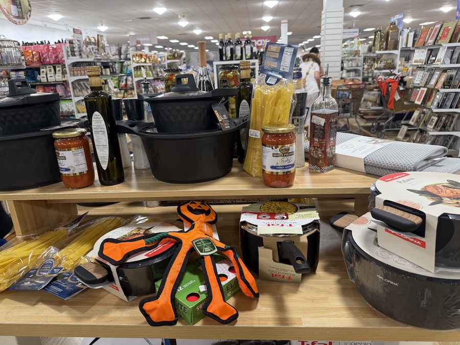 A kitchen aisle display features a variety of pots, pans, and food items.