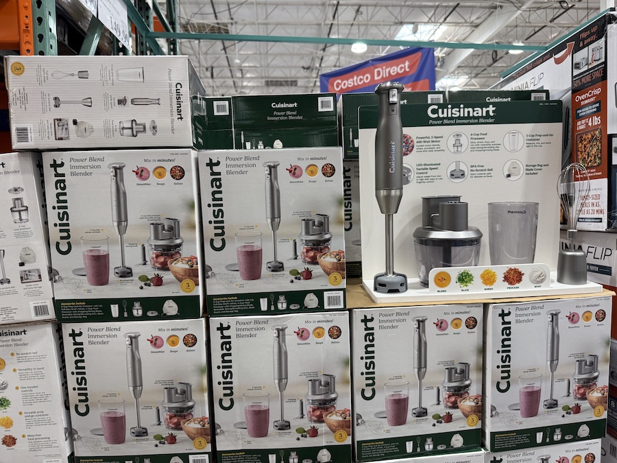 Stainless steel handheld immersion blender with attachments beside a smoothie glass.