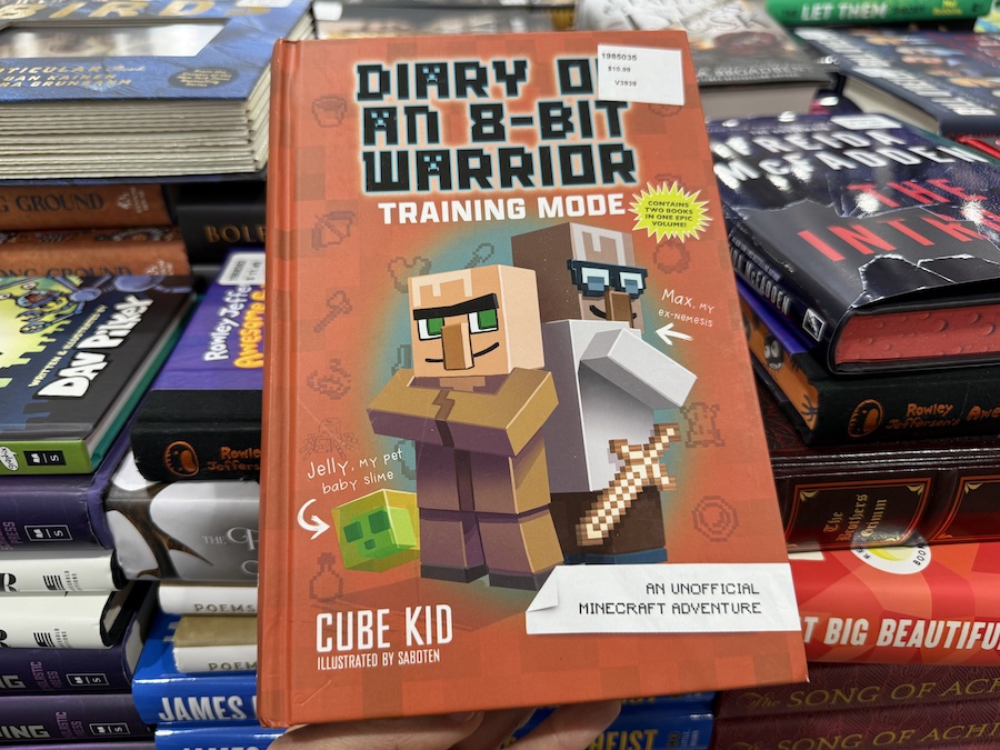 “Diary of an 8-Bit Warrior: Training Mode” books by Cube Kid arranged in a display rack in the book section.