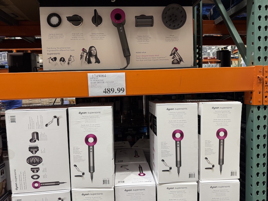 Stylish Dyson hair dryer with magnetic attachments arranged beside its sleek stand.