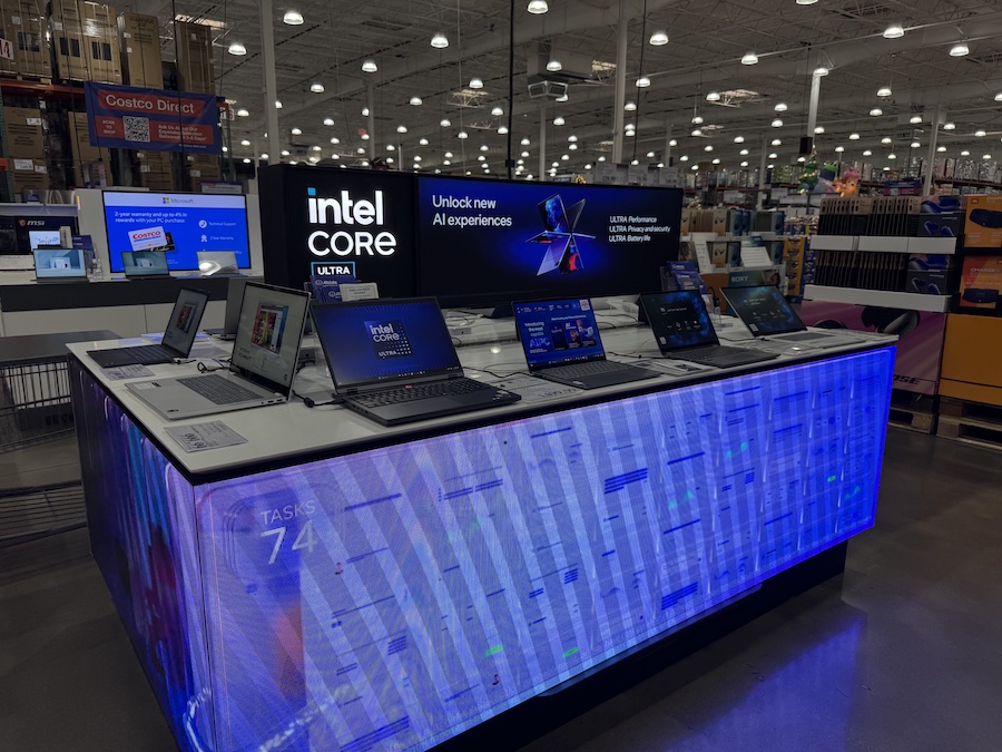 Table with notebooks and Intel Core promotional setup showcasing Costco’s tech and stationery offers.