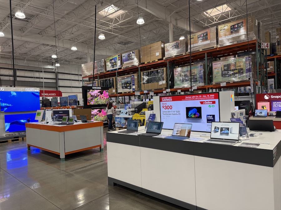 Lenovo Slim 7i 14" OLED Touchscreen Copilot+ PC displayed on a Costco tech table beside other laptops.