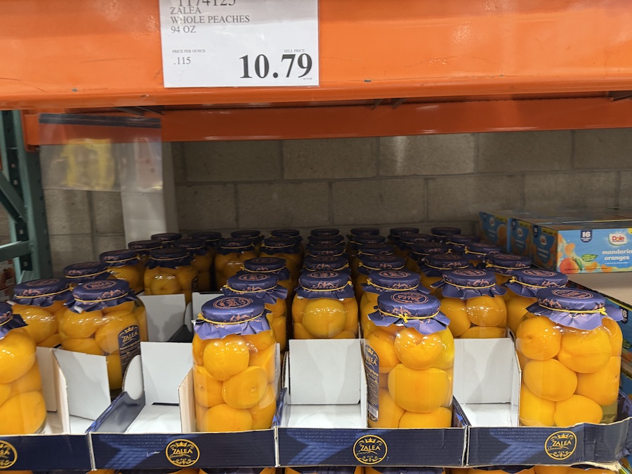 Large glass jar of tender peaches preserved in light syrup.