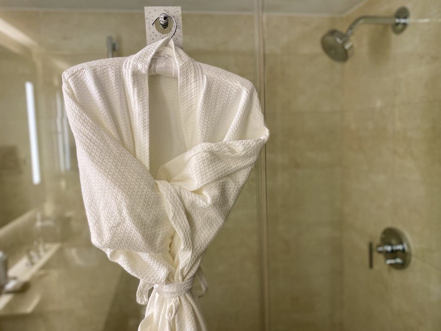 A bathrobe is hanging on the shower stall.