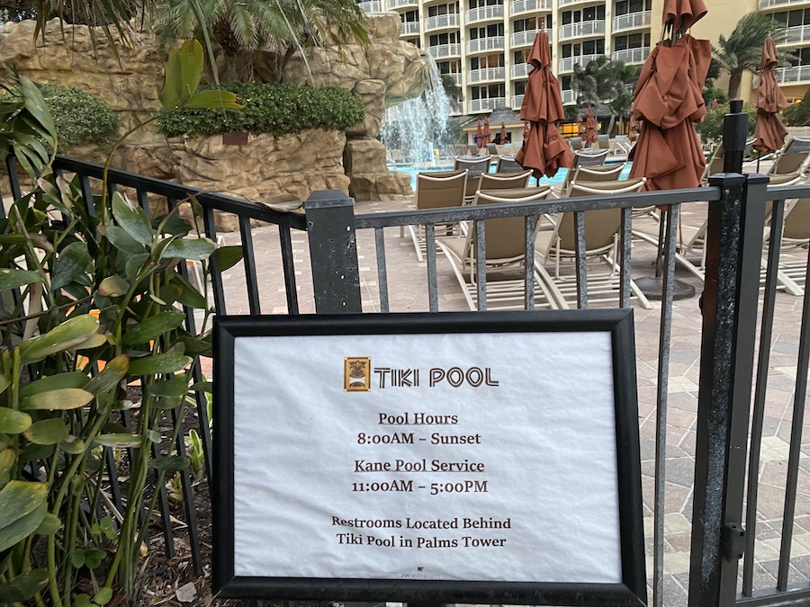 A close-up view of a sign reading "TIKI POOL" with pool hours.
