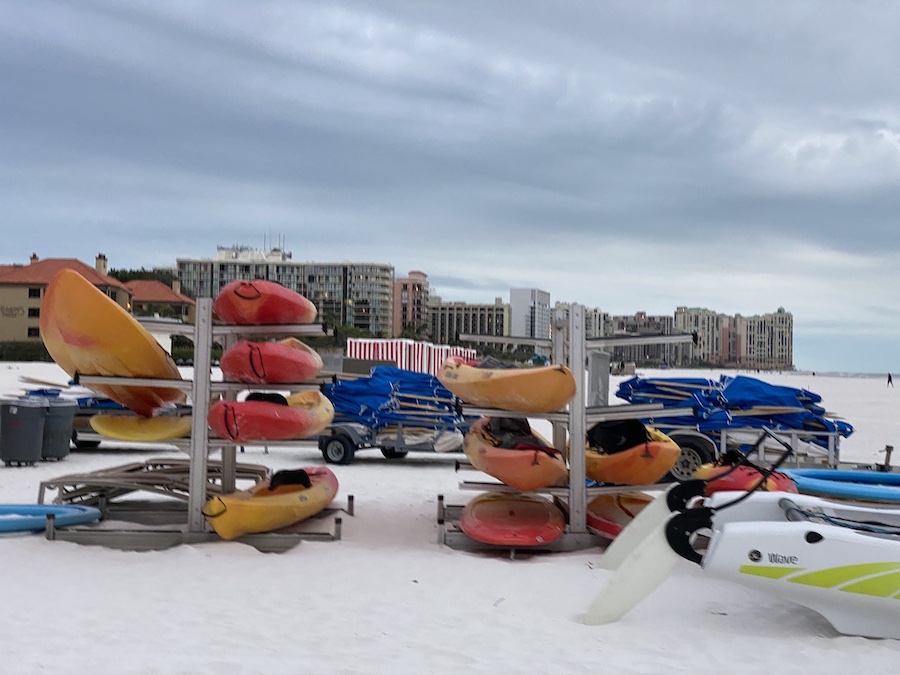 Kayaks resting on the sand beside the gentle surf at Marco Island Beach.