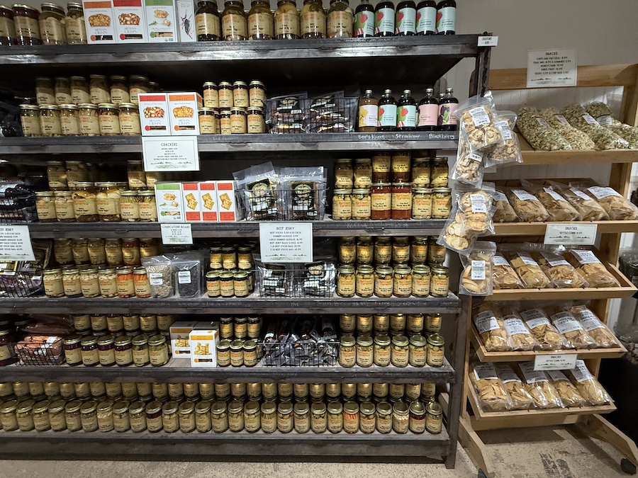 Colorful jars of canned vegetables neatly arranged on rustic wooden shelves.