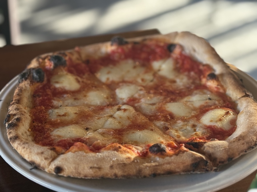 Pizza from Grumpy Sicilian, showing crispy crusts, melted cheese, and colorful toppings.