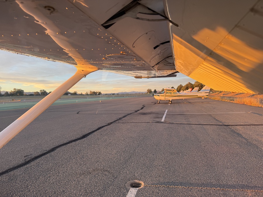 Several small planes lined up along the runway at Payson Airport, with clear blue skies and scenic desert hills surrounding the airfield.