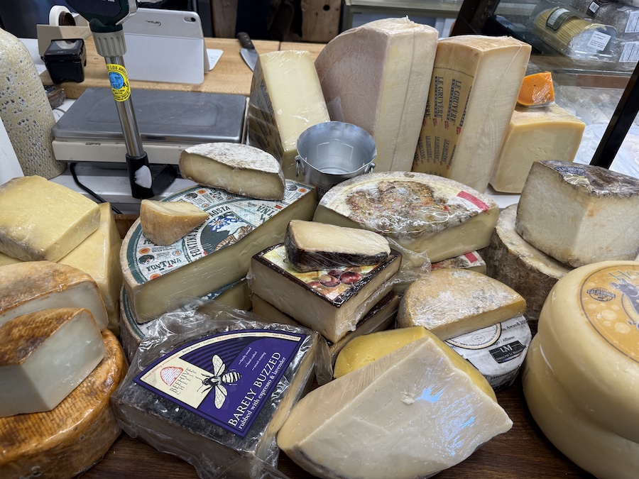 Display of artisan cheeses stacked beautifully on wooden shelves.