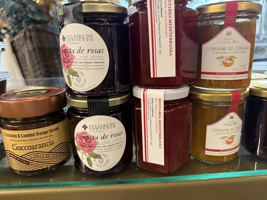 Shelves lined with gourmet jams and artisan preserves beside cheese displays.