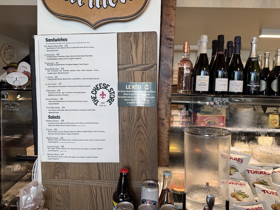 Display of freshly made sandwiches stacked beside wedges of cheese.