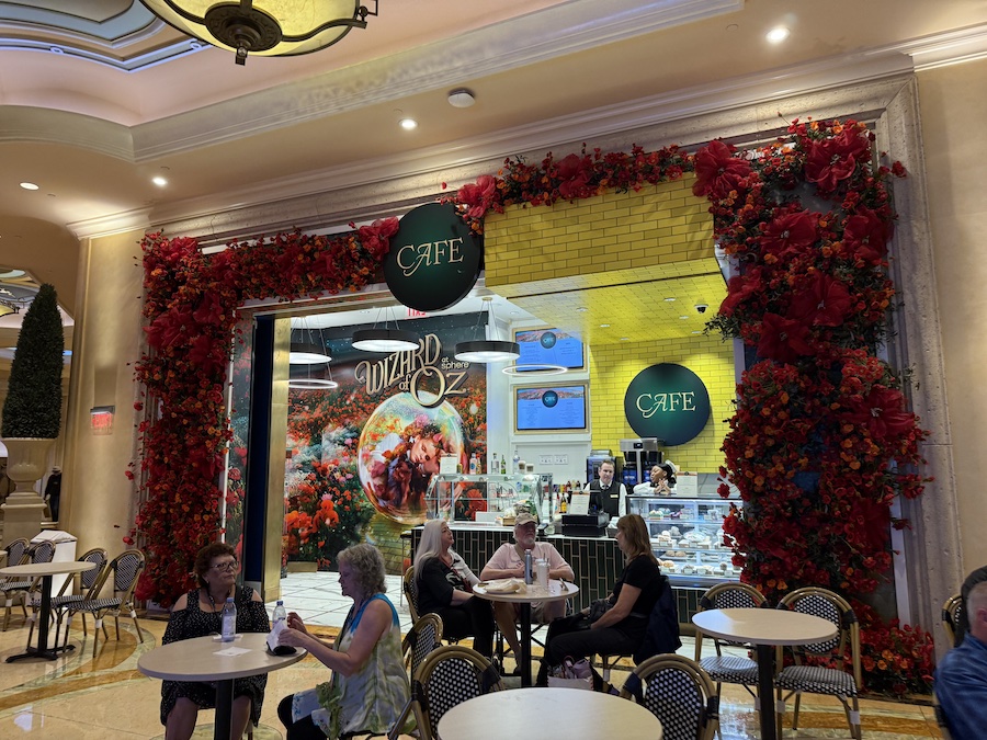 The entrance to a themed cafe decorated with lush red flowers and ribbons framing the doorway.