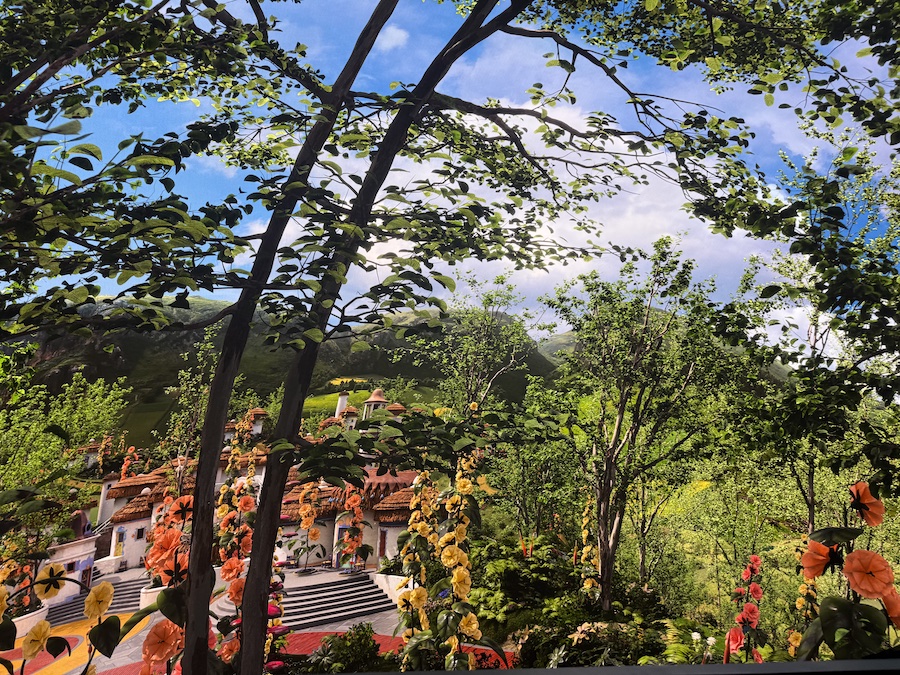 A highly detailed, vibrant green and orange landscape, viewed as if looking through lush green tree branches and foliage.