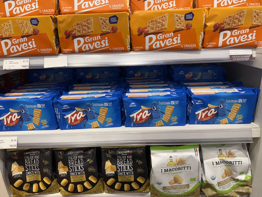 Stacks of Italian crackers in colorful boxes neatly displayed along Eataly’s grocery aisles.