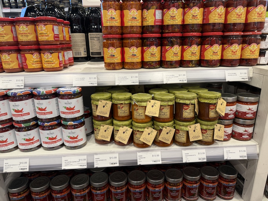 Assorted jars of Italian hot peppers and chili spreads adding vibrant red tones to the gourmet shelves.