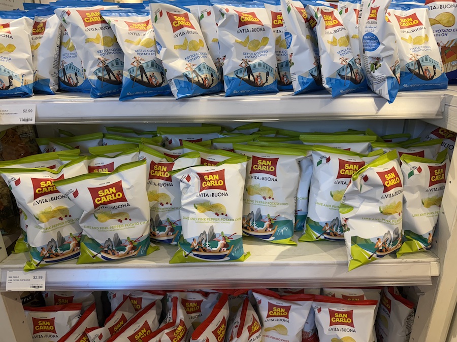 Rows of San Carlo potato chips in signature white and red packaging on a snack display rack.