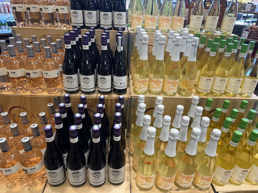 Elegant wine section with Italian reds and whites displayed on wooden racks.