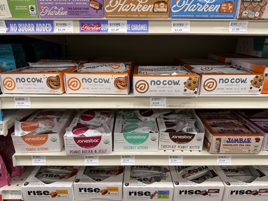 Protein and energy bars from leading brands arranged neatly on a rack for quick grab-and-go snacks.