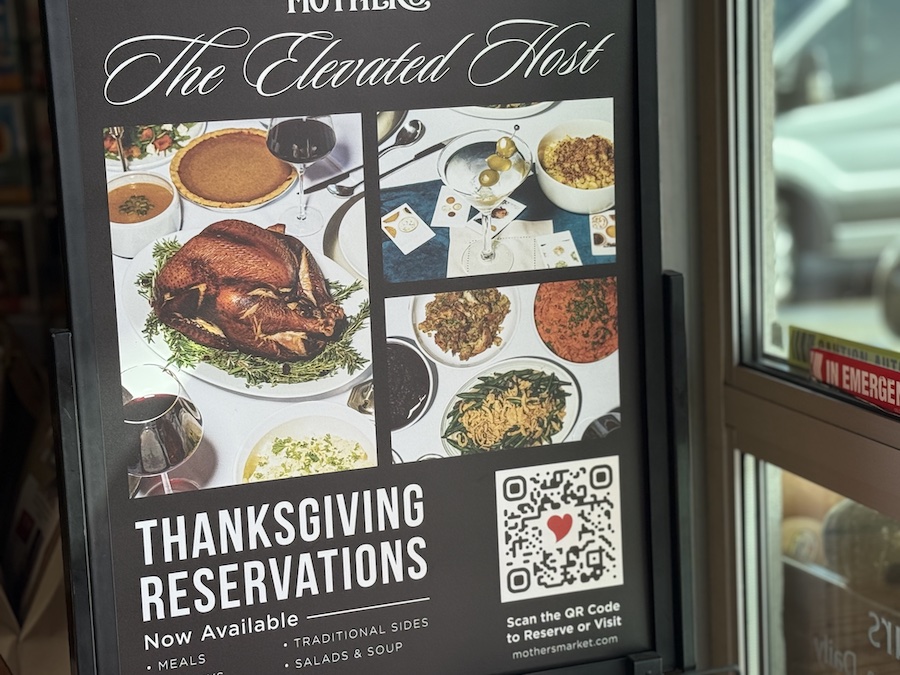 Promotional sign for “The Elevated Host Thanksgiving Reservations” featuring gourmet ingredients and festive decor inside Mother’s California Market.