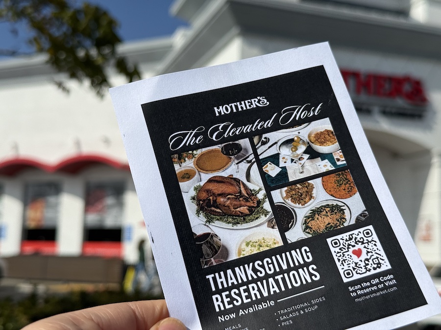 A person holding a flyer for The Elevated Host Thanksgiving Reservations near Mother’s California Market