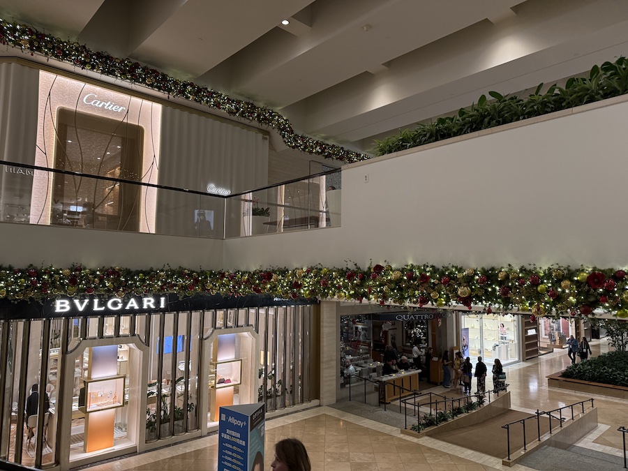 Elegant Christmas decorations inside South Coast Plaza, featuring shimmering garlands, golden ornaments, and twinkling string lights creating a luxurious seasonal atmosphere.