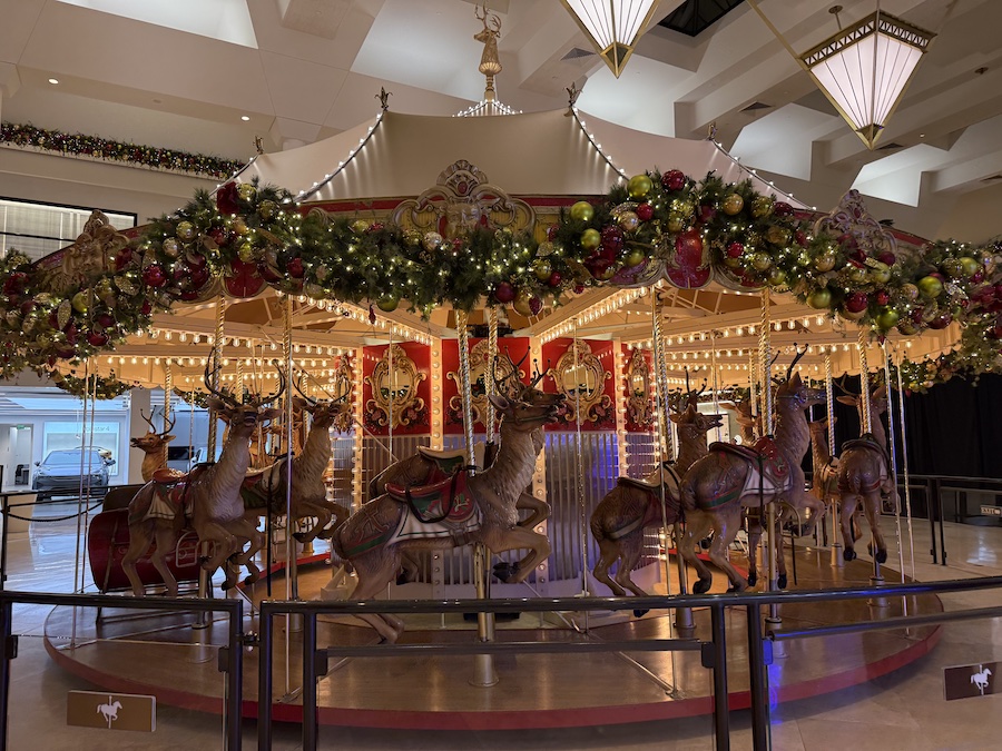 A festive Christmas carousel inside South Coast Plaza adorned with twinkling lights, red and gold garlands.