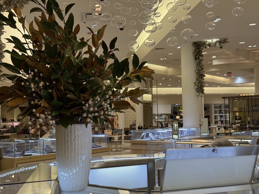 A spacious shopping hall at South Coast Plaza, lined with high-end stores, polished marble floors, and elegant lighting.