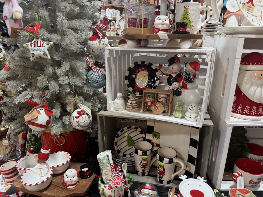 Ceramic Christmas dishes featuring seasonal patterns and colors, stacked on store shelves.