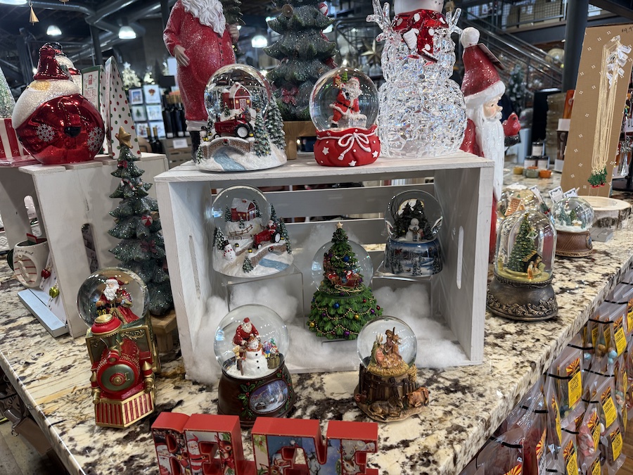 Glass snow globes arranged neatly on shelves, each filled with wintry scenes and glittering snow.