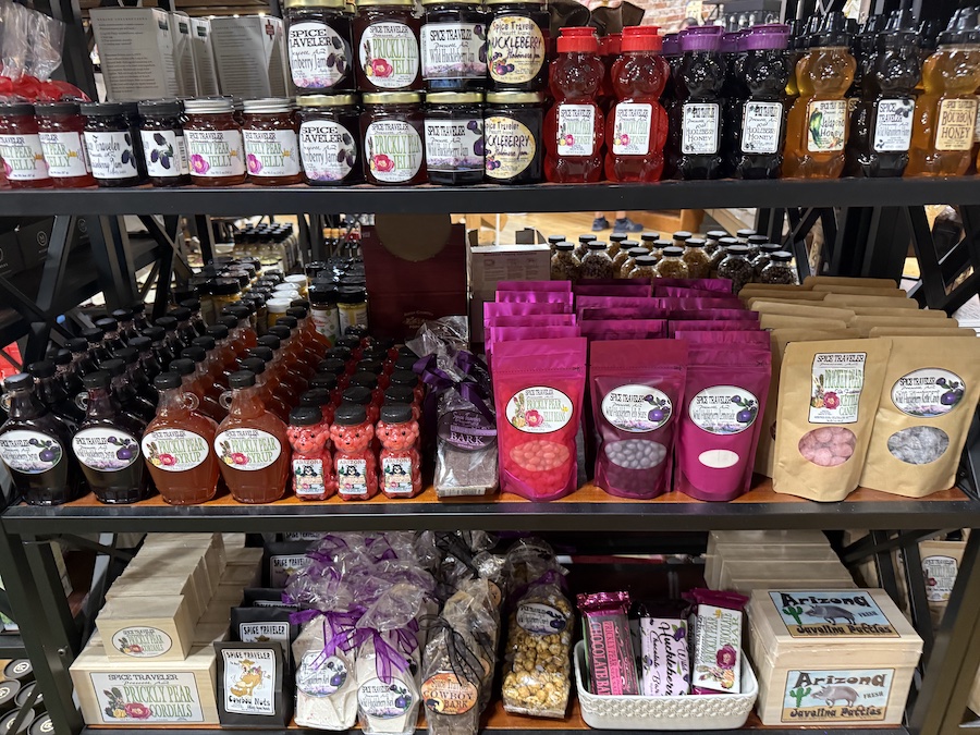 A colorful assortment of jams, honey, syrups, jelly beans, kettle candy, nuts, and chocolate bark lining the gourmet shelves at Spice Traveler Prescott.