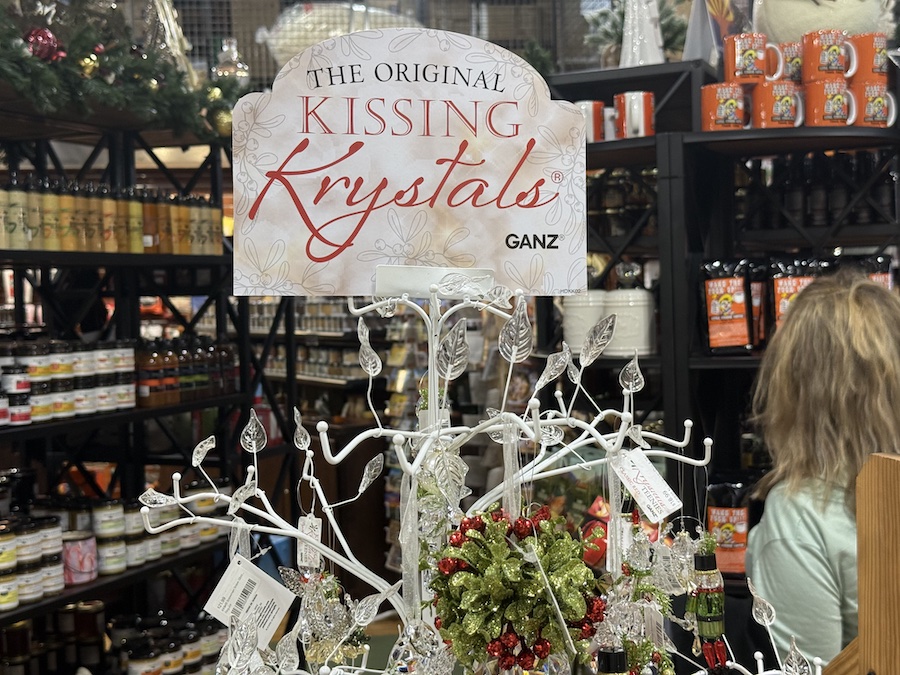 Kissing Krystals ornaments by Ganz sparkling under store lighting on a decorative display branch.