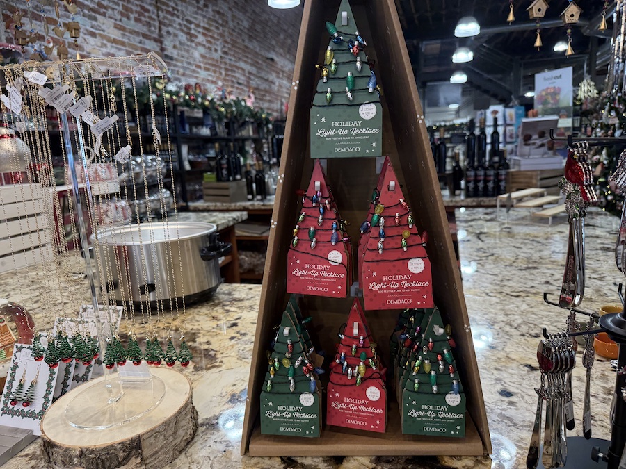 Light-up holiday necklaces hanging on a display rack, glowing with colorful festive lights.