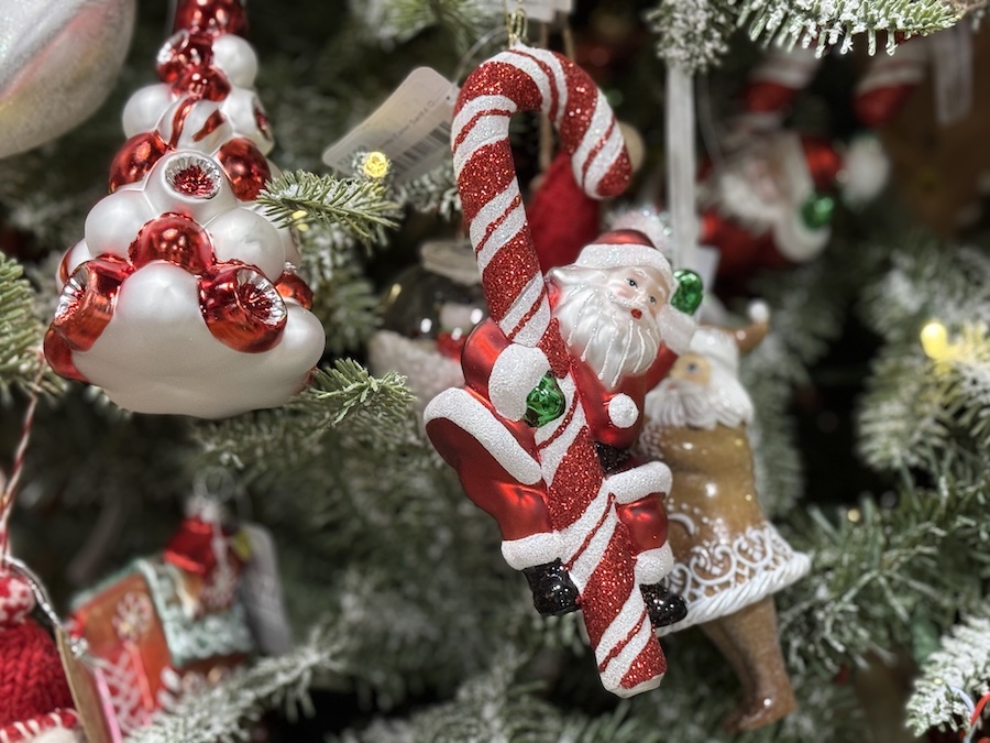 Santa ornament with red and white staff hanging among classic holiday décor on a Christmas tree.